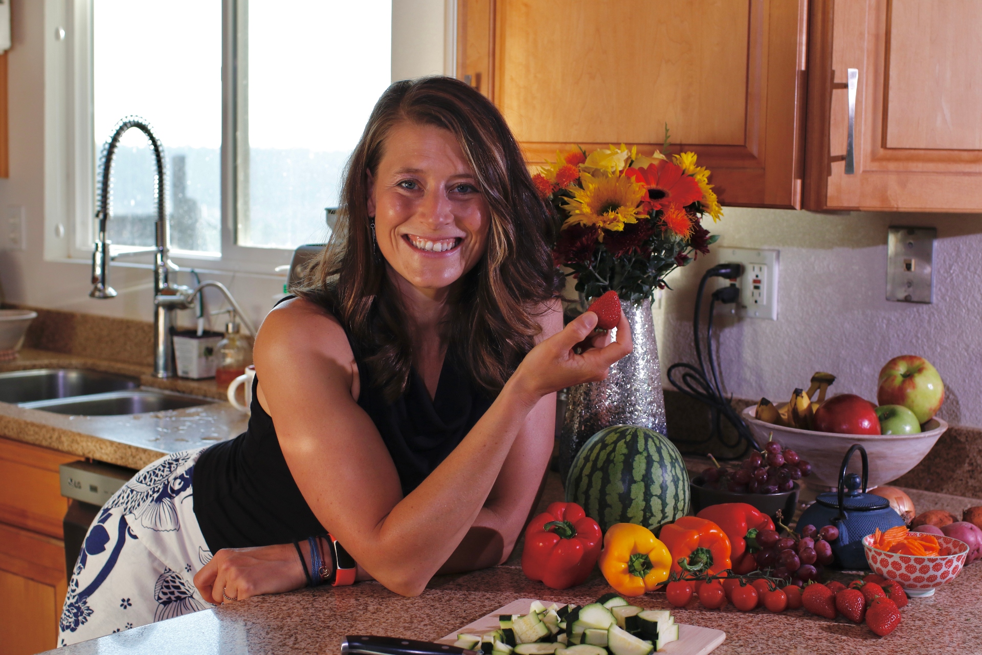 Lin smiling in her kitchen with colorful fresh produce
