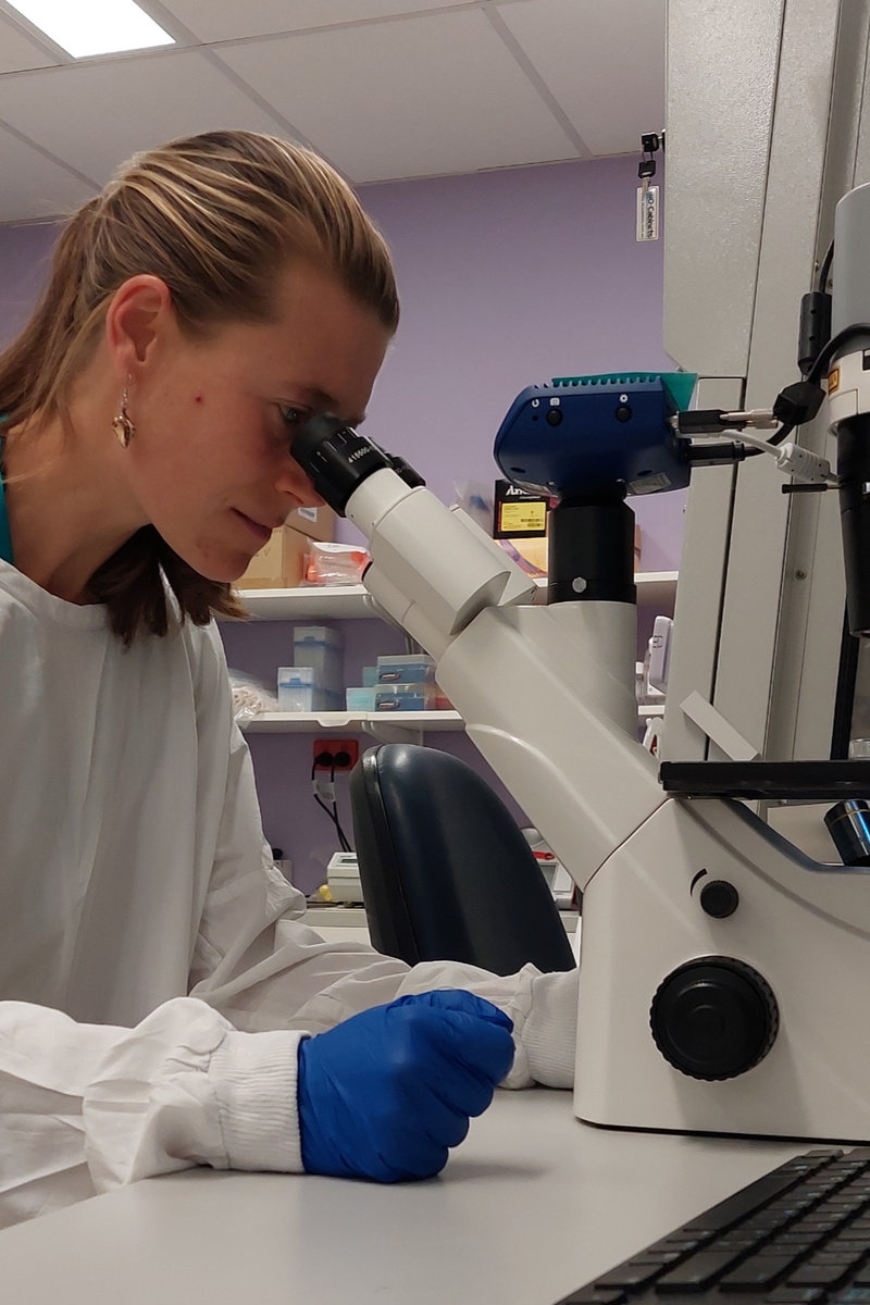 Lin looking through a microscope in the lab